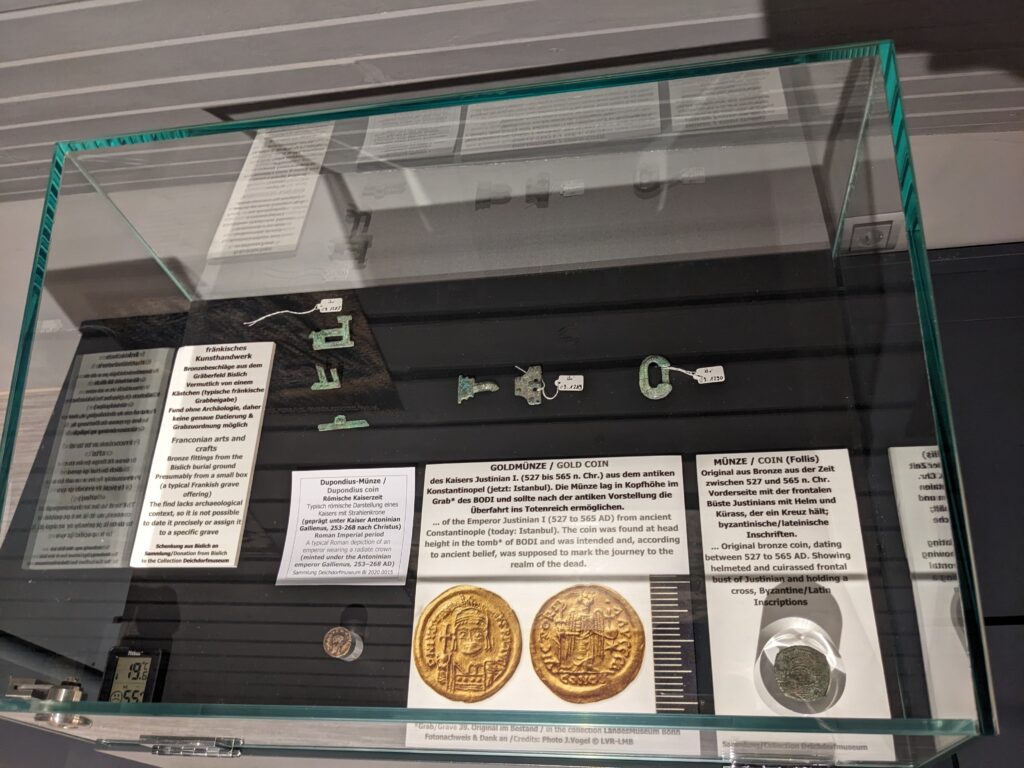 In einer Vitrine sind verschiedene historische Münzen und Objekte aus Gold und Silber ausgestellt.