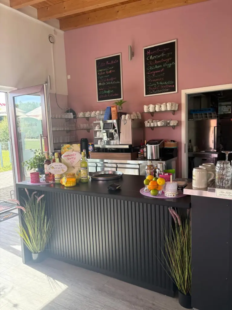 Theke eines gemütlichen Cafés mit verschiedenen Getränken, Snacks und einer übersichtlichen Speisekarte an der Wand.